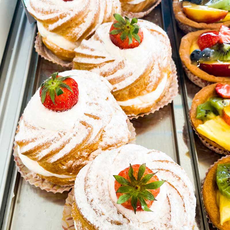 pasticceria. I nostri pasticcini. Bignè ripieni di panna e con una gustosissima fragola. Cartellette con crema pasticciera e frutta